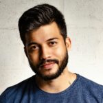 Close-up portrait of a handsome man with a beard in casual attire, smiling warmly.