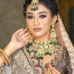 A bride adorned with traditional Indian jewelry and attire in a graceful pose.